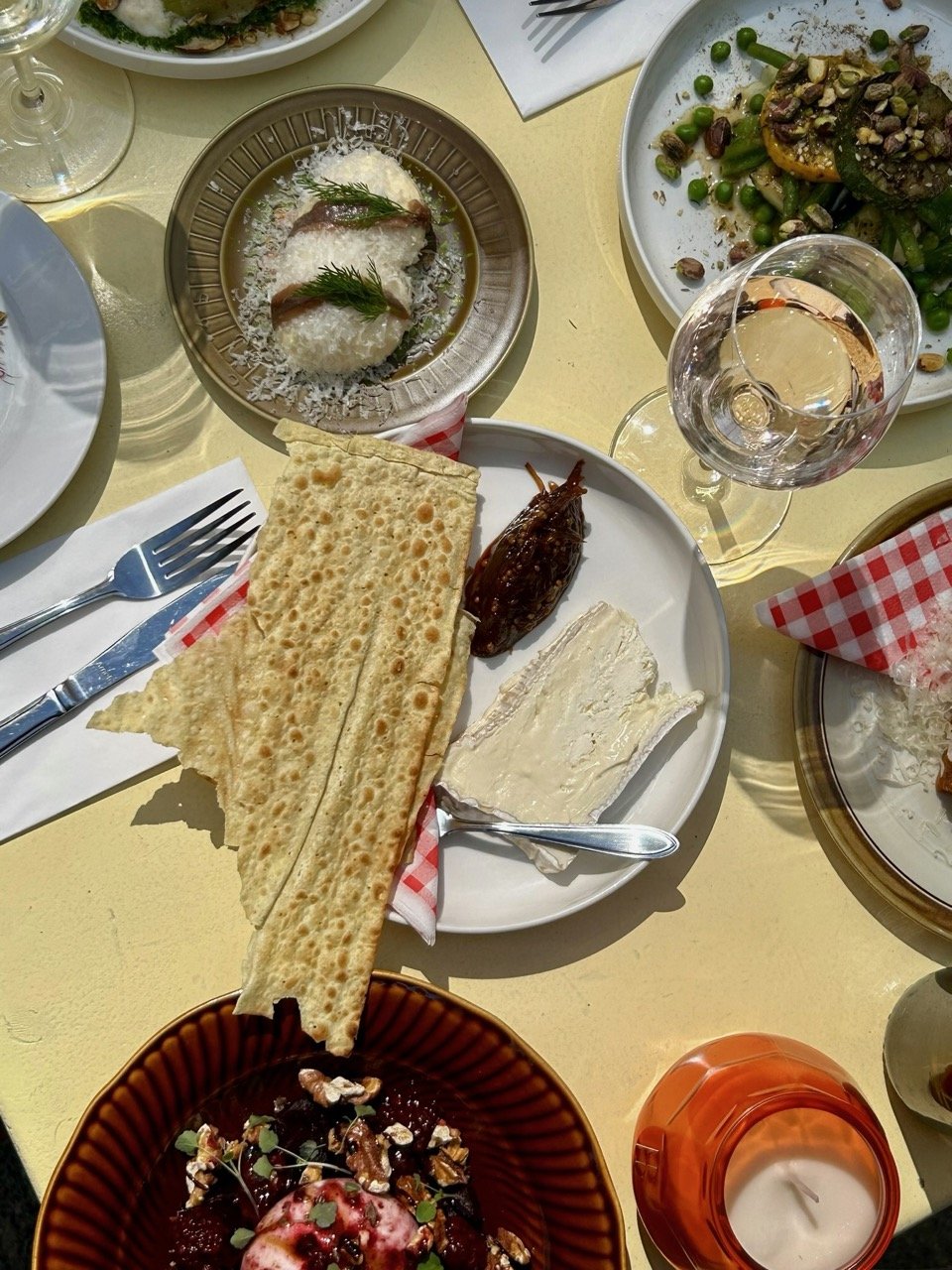 Verschillende gerechten op een tafel, inclusief platbrood, kaas, gedroogde vijg, salade met peulen, en een dessert met bessen en noten.