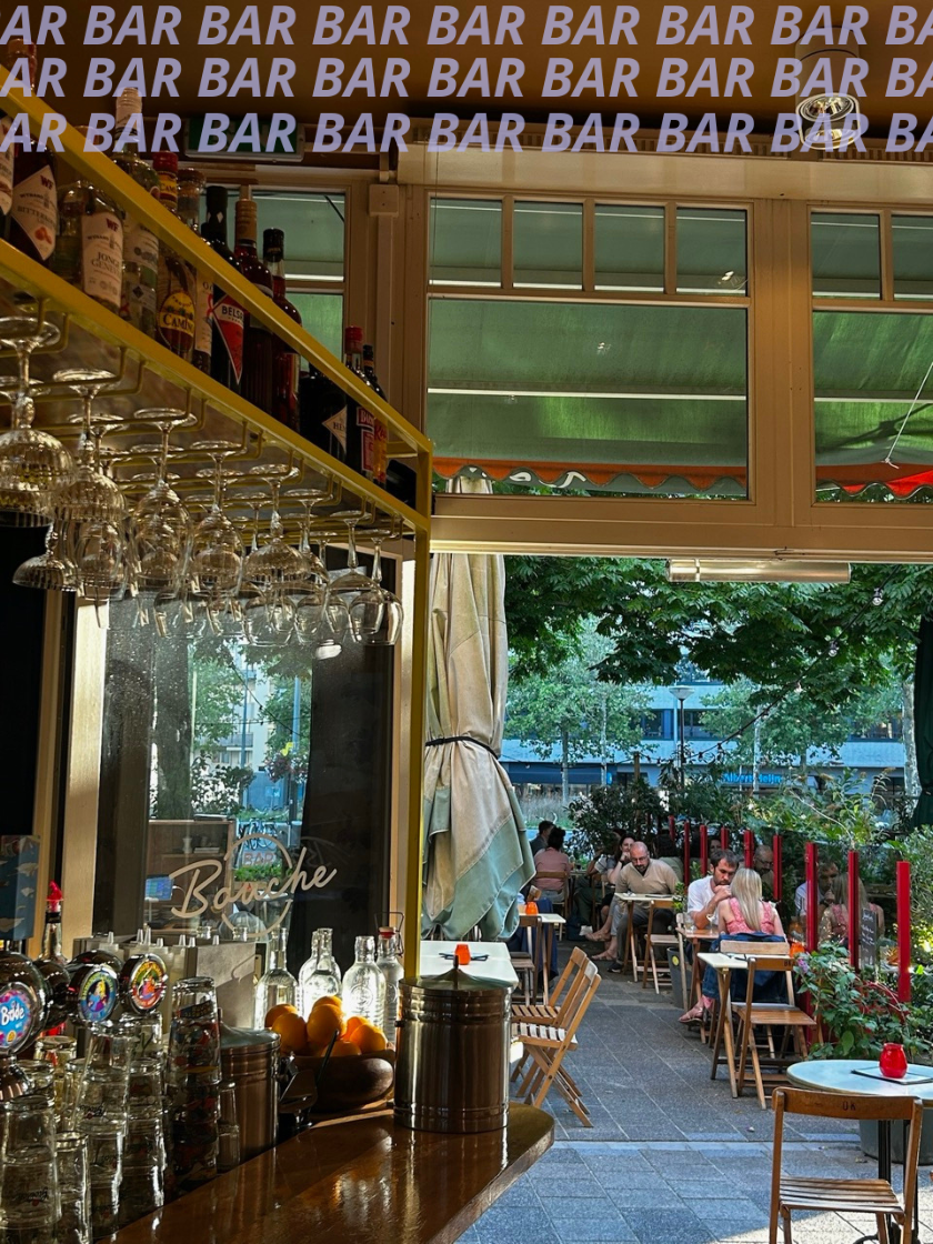 Binnen en buiten terras van een bar en restaurant met mensen die eten en drinken. Bomen en gebouwen buiten zichtbaar.